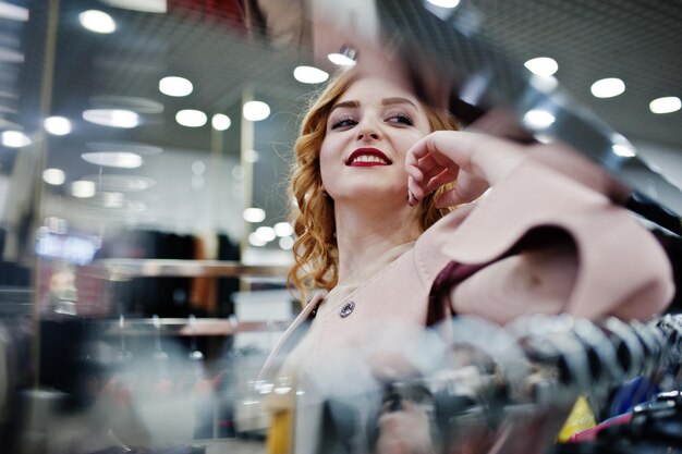 Chica rubia de elegancia en abrigo en la tienda de abrigos de piel y chaquetas de cuero