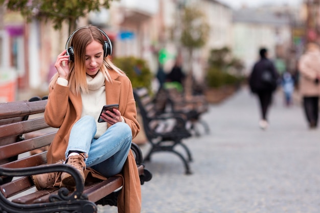 Chica rubia escuchando música en auriculares con espacio de copia