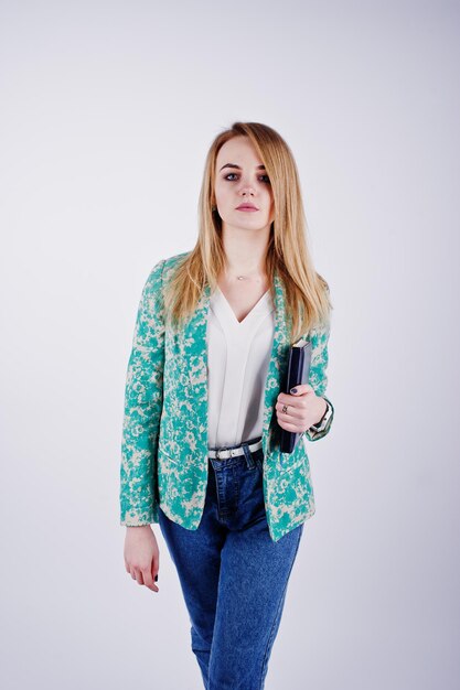 Chica rubia con estilo en chaqueta y jeans con diario de cuaderno en las manos contra fondo blanco en el estudio