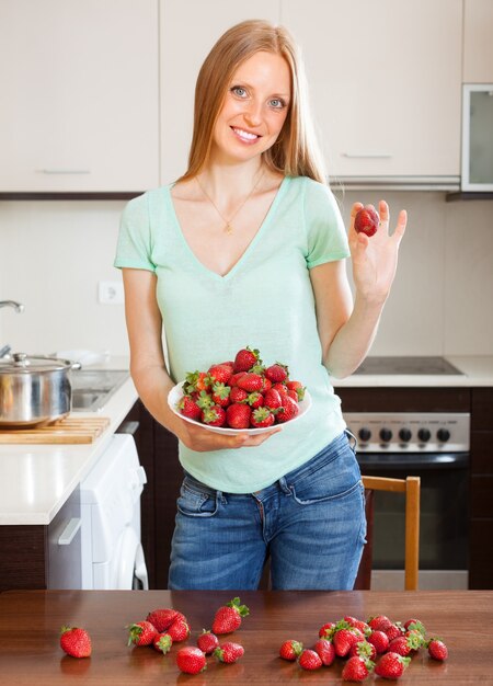 Chica rubia feliz celebración de fresas