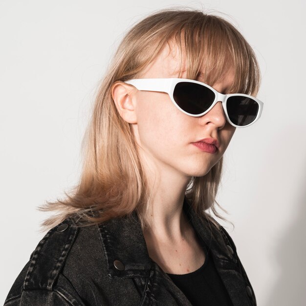 Chica rubia con gafas de sol blancas sesión de fotos de moda para adolescentes