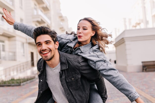 Chica rubia inspirada disfrutando de un paseo con su novio. Adorable dama pasar tiempo con su marido al aire libre.