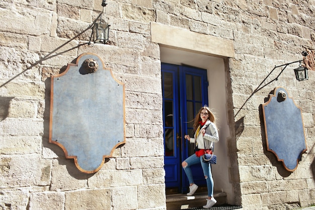 Chica rubia en jeans azul se encuentra ante una puerta azul