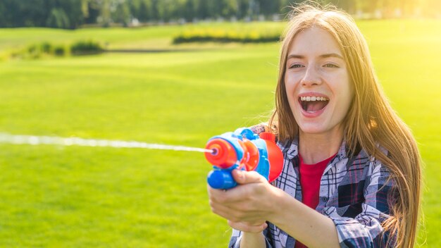 Chica rubia jugando con pistola de agua