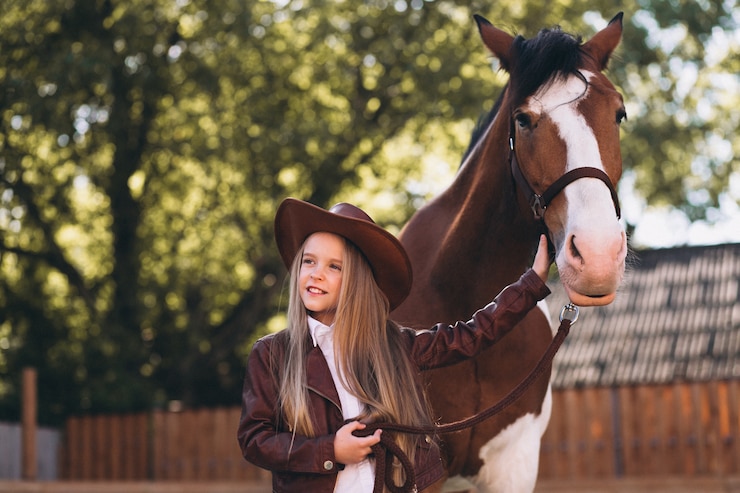 Foto gratuito una chica rubia linda con un caballo en el rancho.