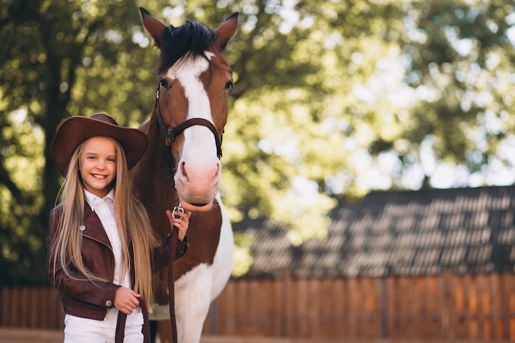 Foto gratuito una chica rubia linda con un caballo en el rancho.