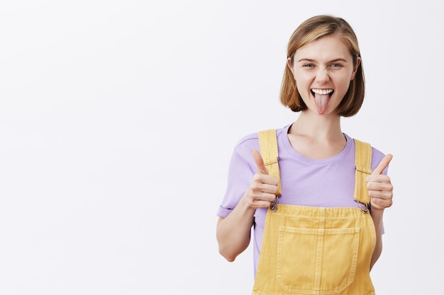 Chica rubia linda descarada diciendo que tienes esto, elogia la buena elección, mostrando el pulgar hacia arriba y sonriendo encantada