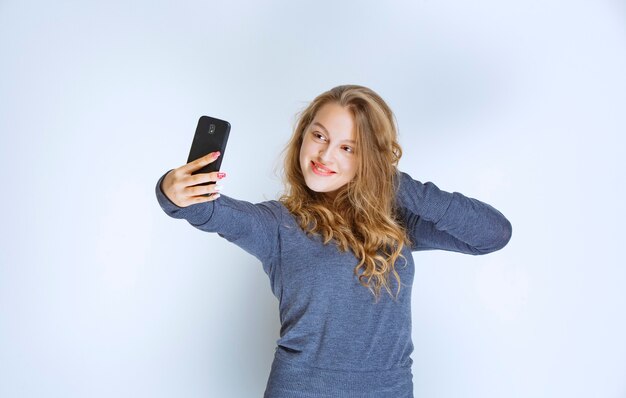 Chica rubia de pelo rizado tomando su selfie.