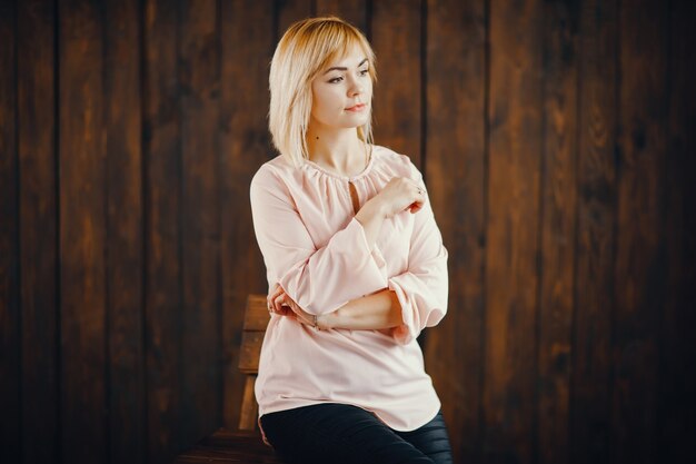 chica rubia de pie junto a una pared