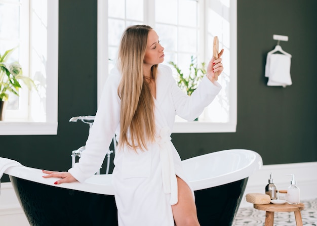 Chica rubia posando en el baño con albornoz