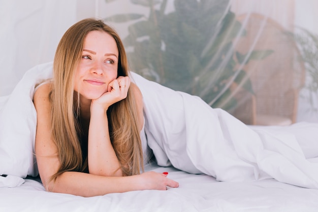 Chica rubia posando en la cama