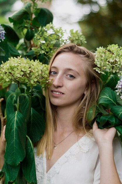 Chica rubia posando con flores junto a su cara