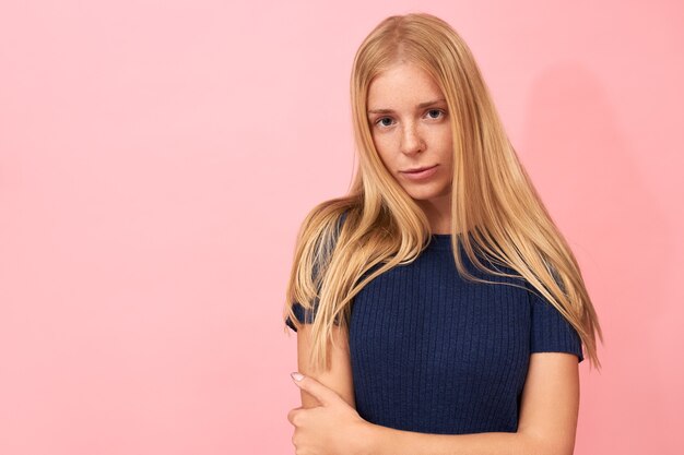 Chica rubia posando con vestido azul en rosa