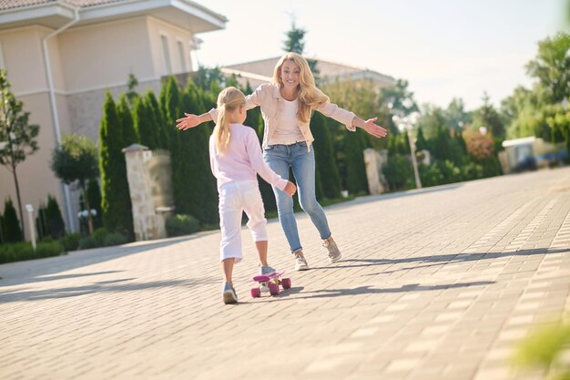 Una chica rubia que intenta andar en patineta y se siente emocionada.