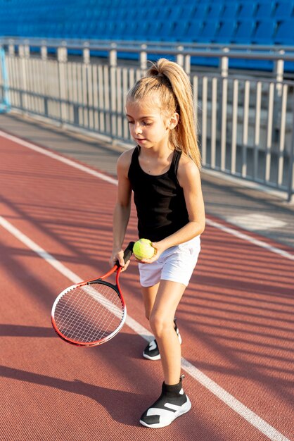 Chica rubia con raqueta de tenis y pelota