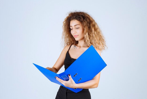 Chica rubia revisando los informes con sorpresa.