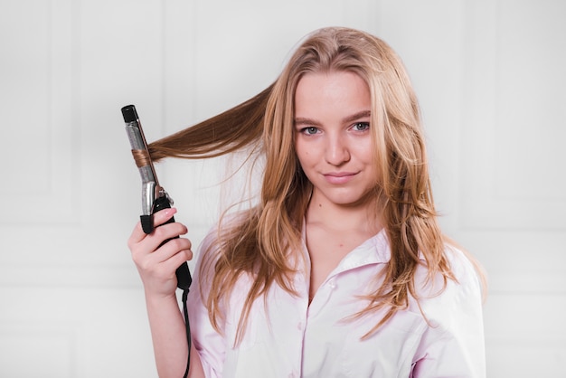 Chica rubia rizándose el pelo