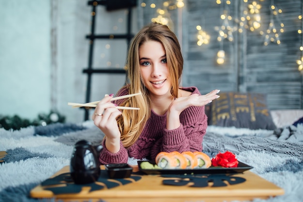 Foto gratuita chica rubia sosteniendo palillos y sonriendo al frente