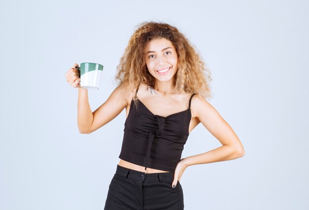 Chica rubia sosteniendo una taza de café como rutina matutina.