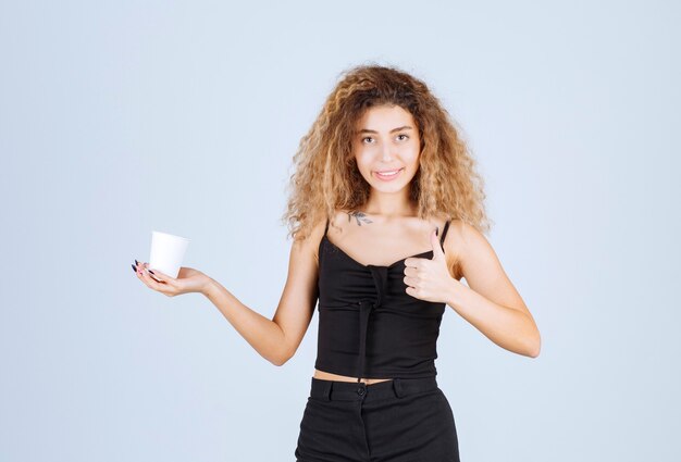 Chica rubia sosteniendo una taza de café y mostrando que le gustaba el sabor.