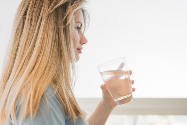 Chica rubia sosteniendo vaso de agua