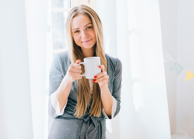 Chica rubia tomando café por la mañana