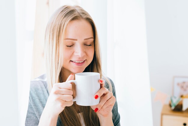 Chica rubia tomando café por la mañana