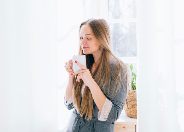 Chica rubia tomando café por la mañana