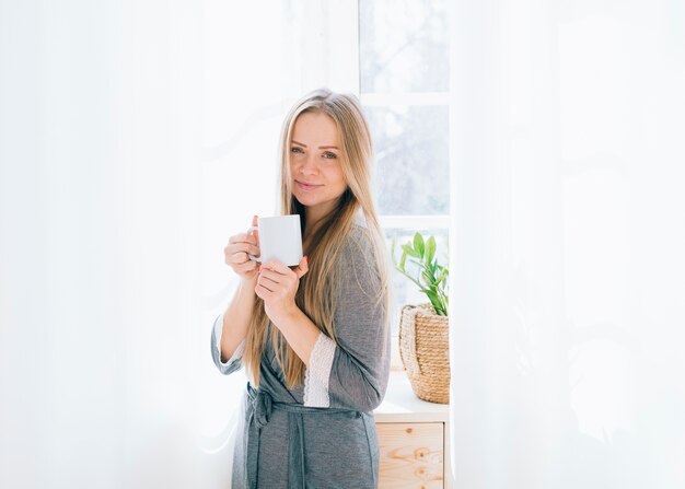 Chica rubia tomando café por la mañana