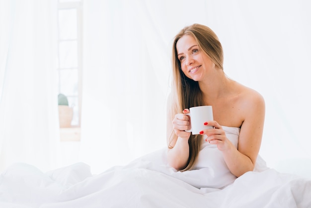 Chica rubia tomando café por la mañana