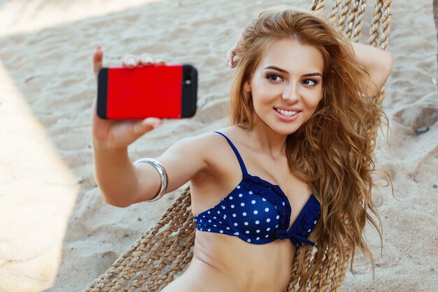 Chica rubia tomándose un selfie en la playa