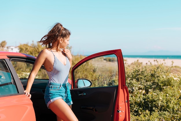 Chica saliendo del coche en la playa