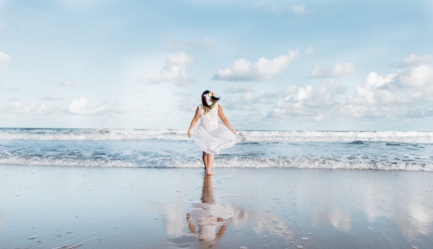 Chica saliendo del mar vistiendo ropa blanca