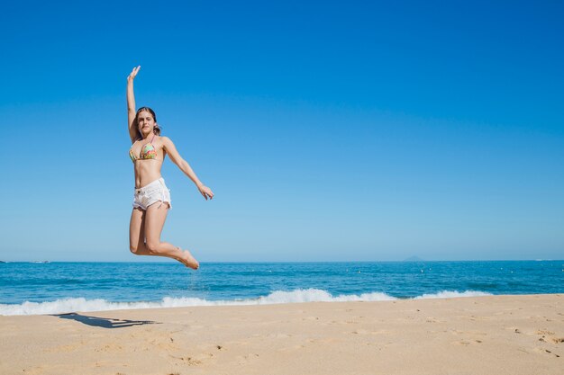 Chica saltando en la playa