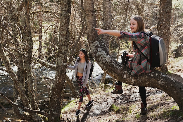 Chica señalando algo a su amiga en el bosque