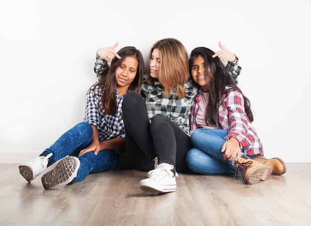 Chica señalando las cabezas de sus amigas