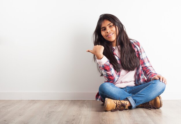 Chica señalando a su lado con el pulgar