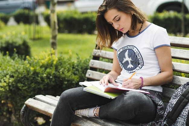 Chica sentada en el banco de escribir en el cuaderno