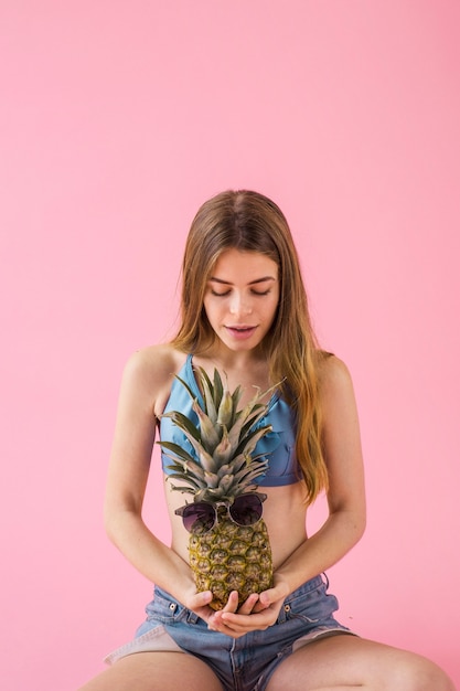 Chica sentada en bikini con piña