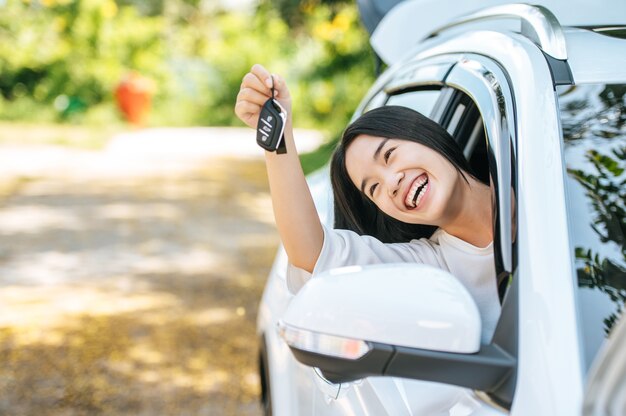 Chica sentada en el coche y sosteniendo las manos de las llaves del coche fuera del coche.