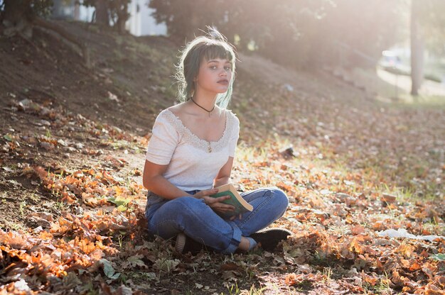 Chica sentada en una colina con un libro en las manos