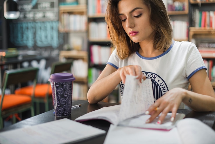 Foto gratuito chica sentada a la lectura de la tabla moviendo la página