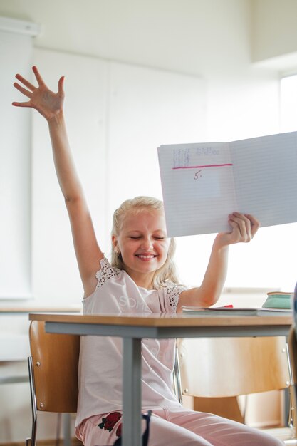 Chica sentada en la mesa de la escuela con el cuaderno