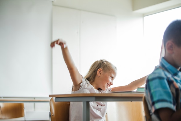 Chica sentada en la mesa de la escuela divertirse