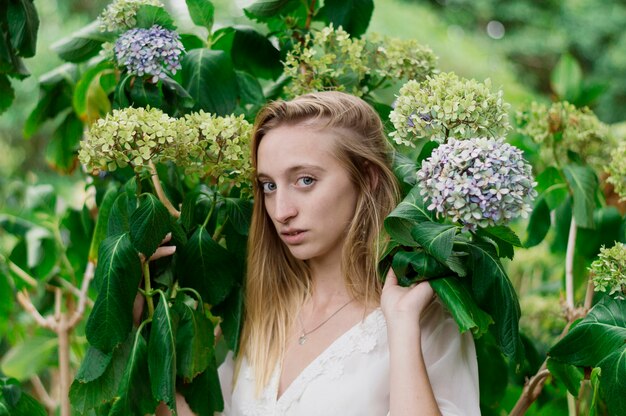 Chica seria posando junto a unas flores