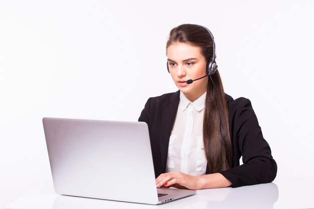 Chica de servicio al cliente joven con un auricular en su lugar de trabajo aislado en la pared blanca