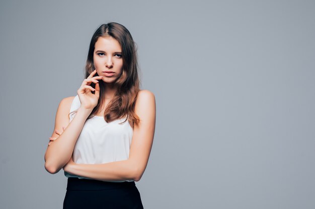 Chica sexy seria en vestido moderno de moda está posando en estudio aislado sobre fondo blanco