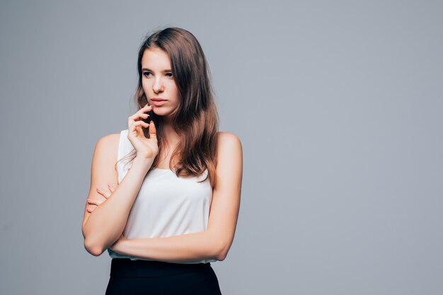 Chica sexy seria en vestido moderno de moda está posando en estudio aislado sobre fondo blanco