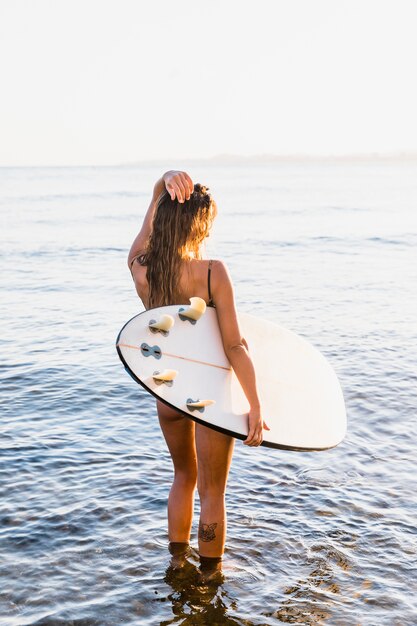 Chica sexy con tabla de surf en la playa