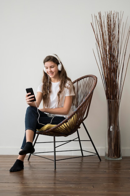 Chica en silla escuchando música en los auriculares